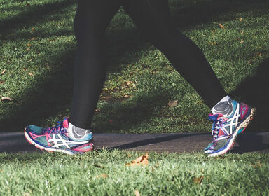 Žena ve sportovní obuvi kráčí parkem. Sportovat můžete už od 1. kroku diety, ale začínejte pomalu a opatrně.