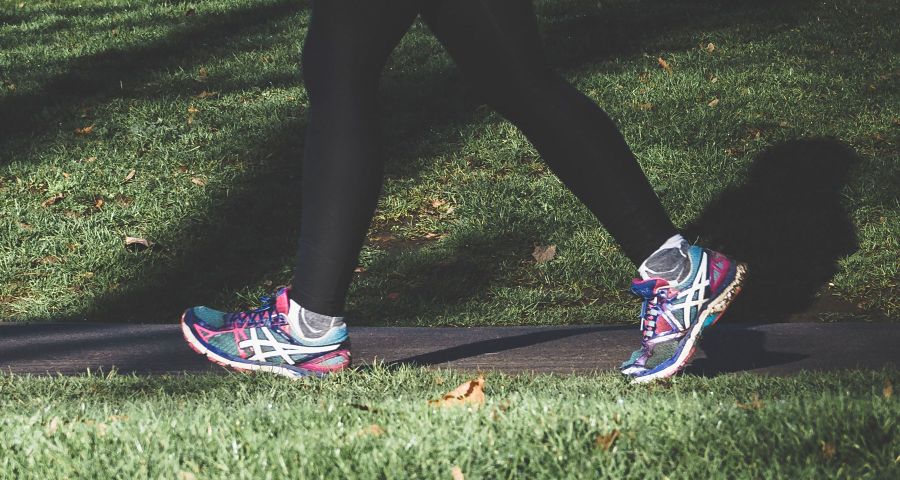 Žena ve sportovní obuvi kráčí parkem. Sportovat můžete už od 1. kroku diety, ale začínejte pomalu a opatrně.