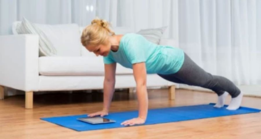 Žena cvičí doma na podložce cvik s vlastní vahou plank.