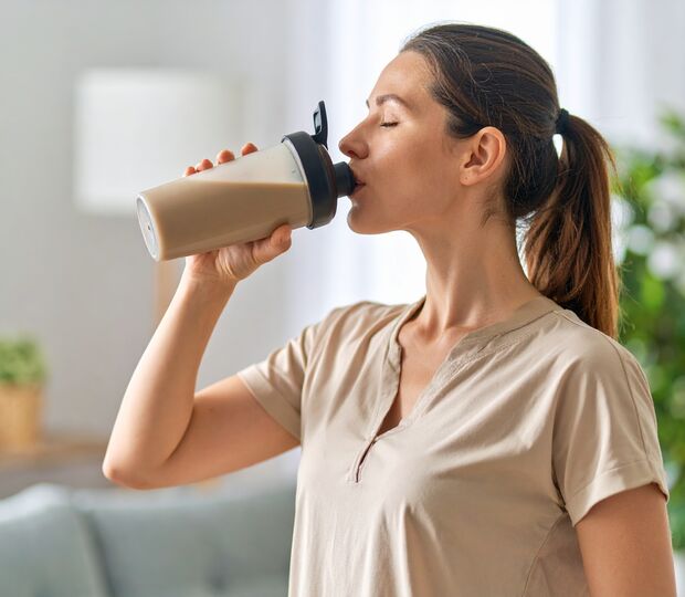 Žena pije proteinový nápoj. Berberin podporuje metabolismus během diety. 