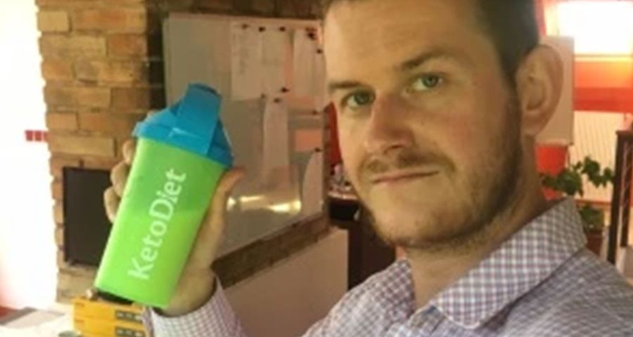 David v kockovanej košeli drží v ruke shaker s proteínovým nápojom KetoDiet.
