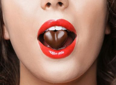 Žena má v ústech čokoládové srdíčko. Skryté cukry na nás číhají téměř všude.