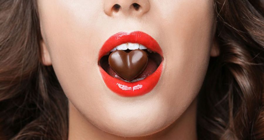 Žena má v ústach čokoládové srdiečko. Skryté cukry na nás číhajú takmer všade.