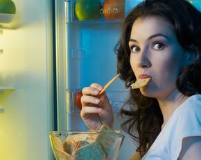 Porušení diety – žena u lednice jí sušenky