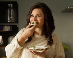 Mladá žena v pletenom svetre sa usmieva. S keto diétou jete pravidelne a nehladujete.