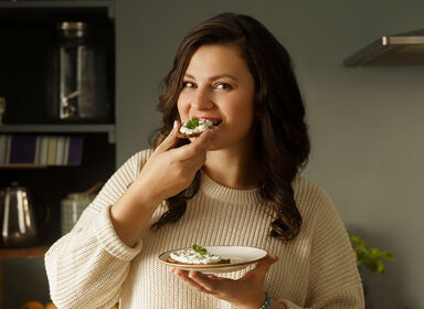 Mladá žena v pleteném světru se usmívá. S keto dietou jíte pravidelně a nehladovíte.