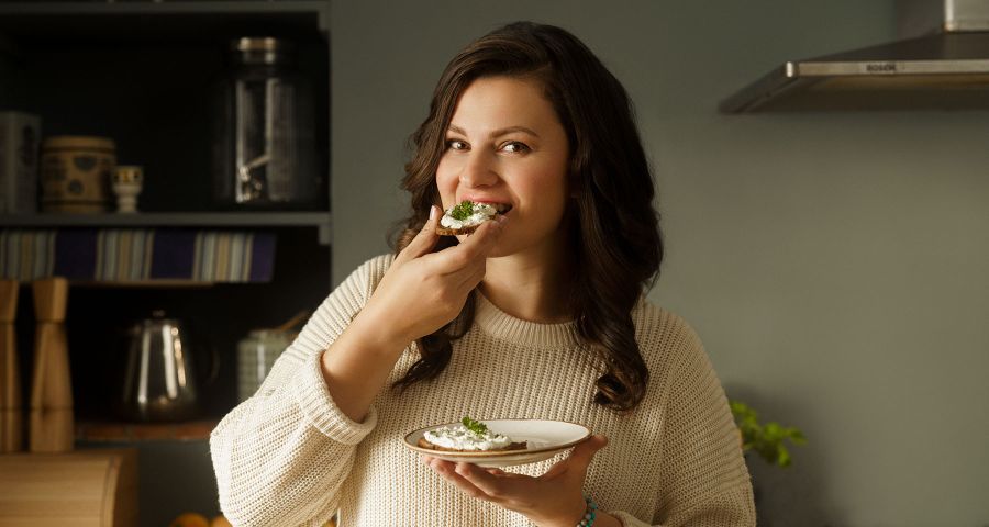 Mladá žena v pletenom svetre sa usmieva. S keto diétou jete pravidelne a nehladujete.